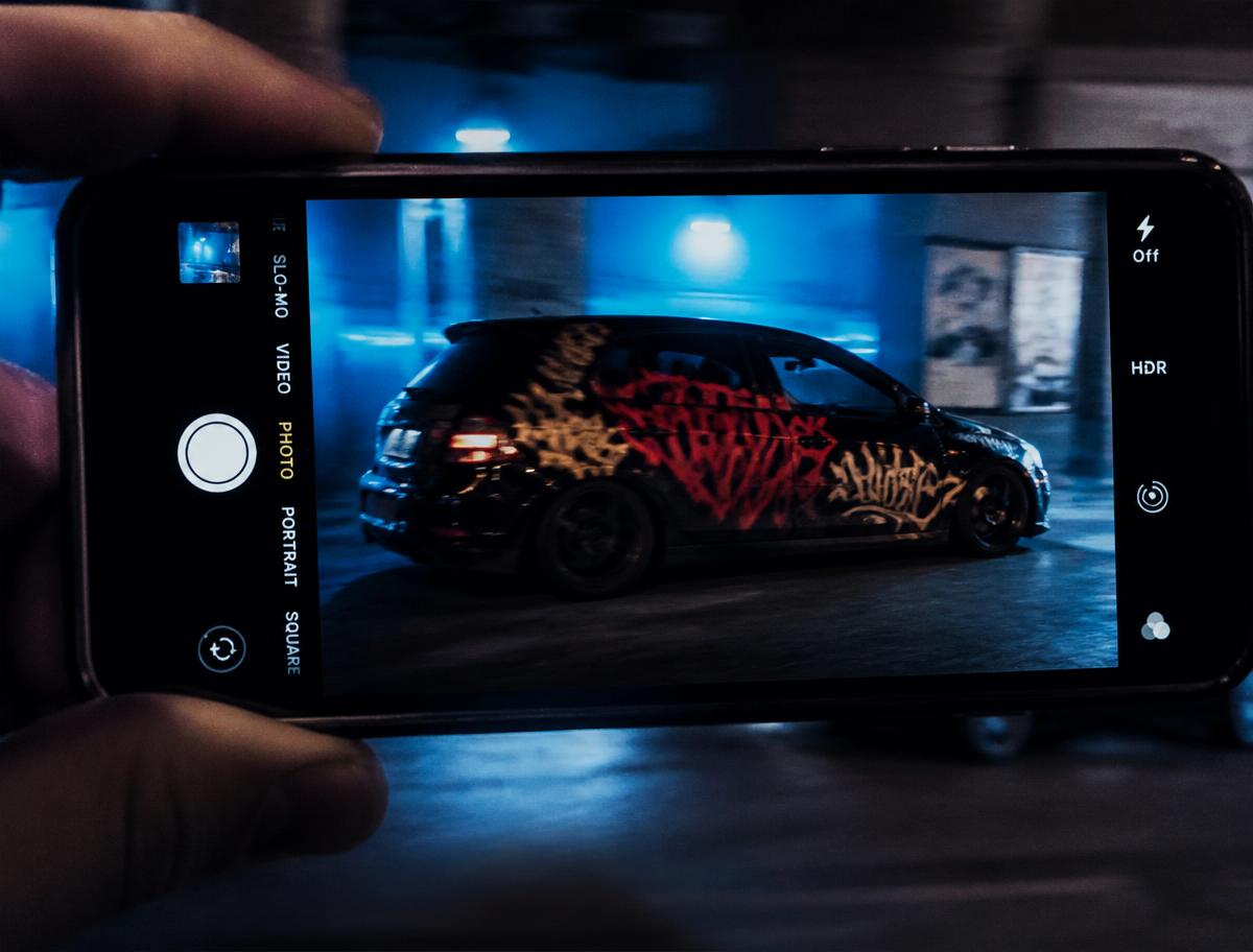 Punkově pomalované auto natáčené mobilem v noci